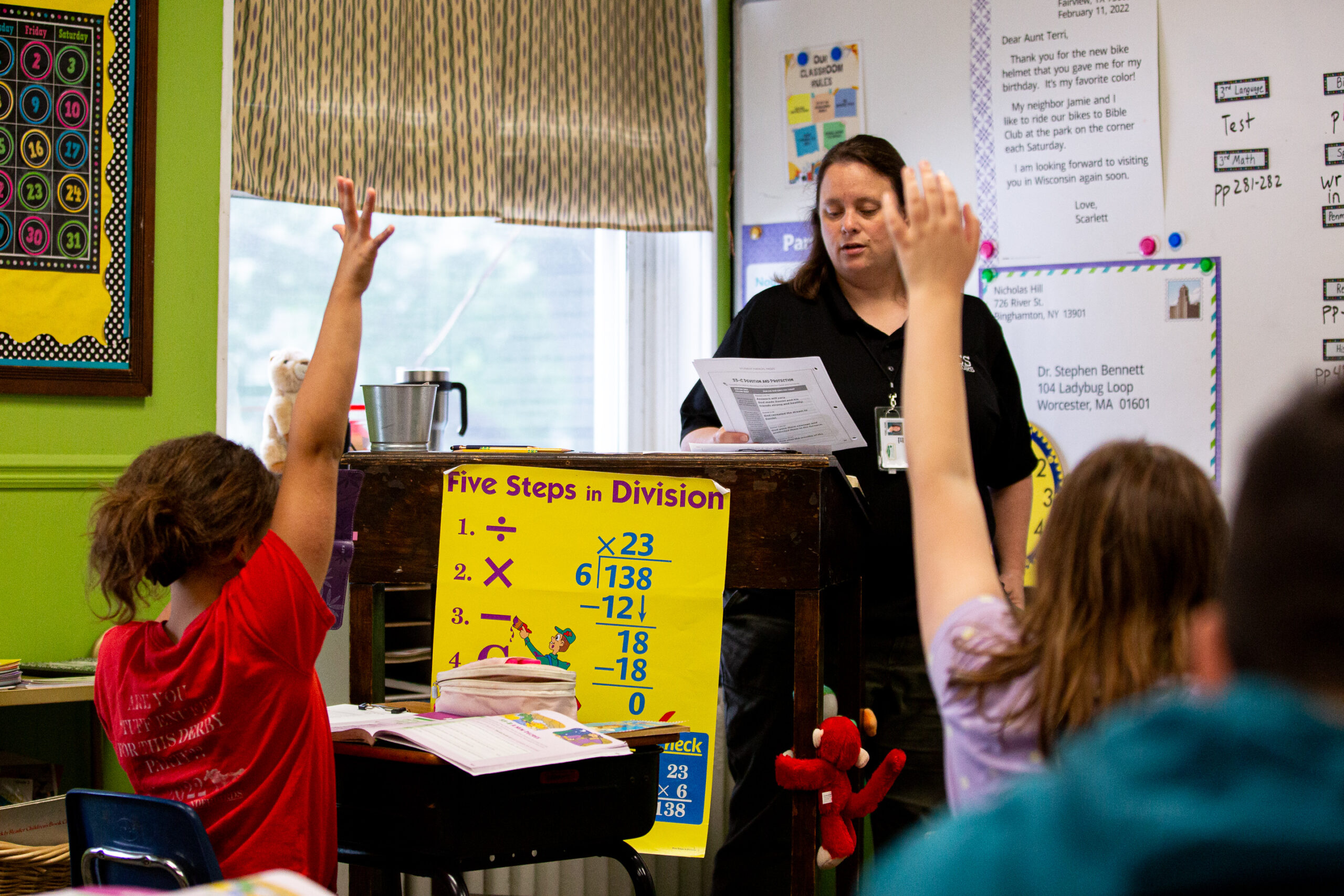 Students raise hands during a classroom division lesson